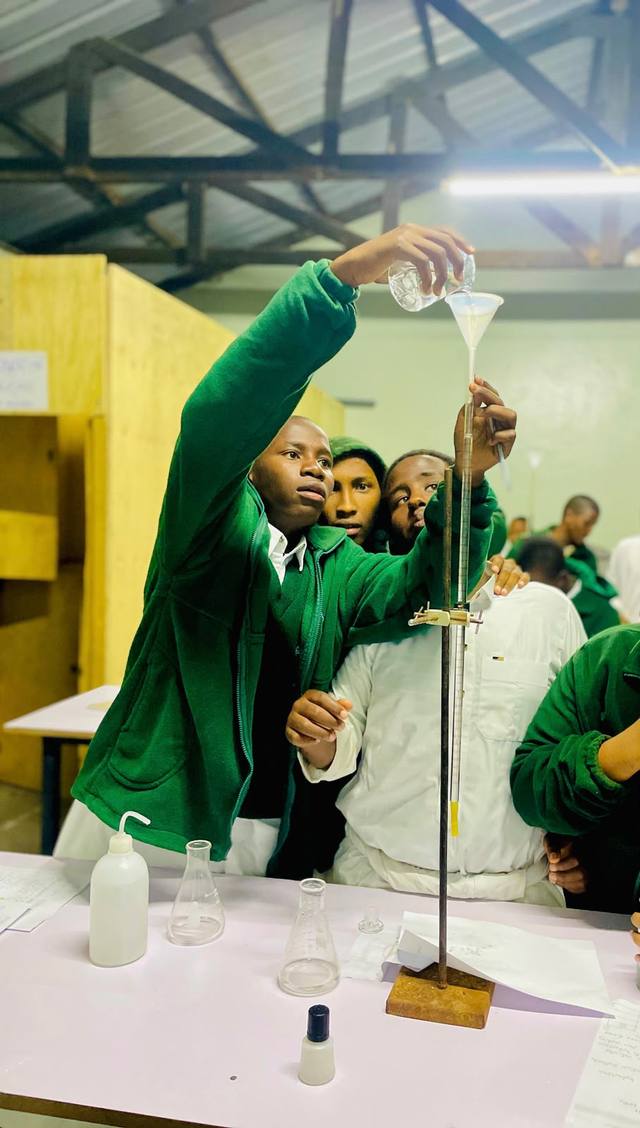 A student pouring liquid through a funnel into a burette in the lab
